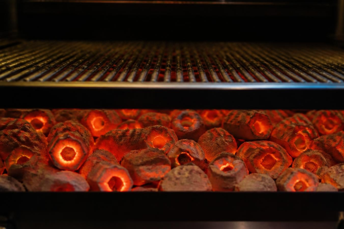 The 4-Step Sawdust Charcoal Manufacturing Process: From Drying to Carbonization 3 Glowing red hot smokeless sawdust charcoal briquettes burning evenly on a commercial restaurant grill
