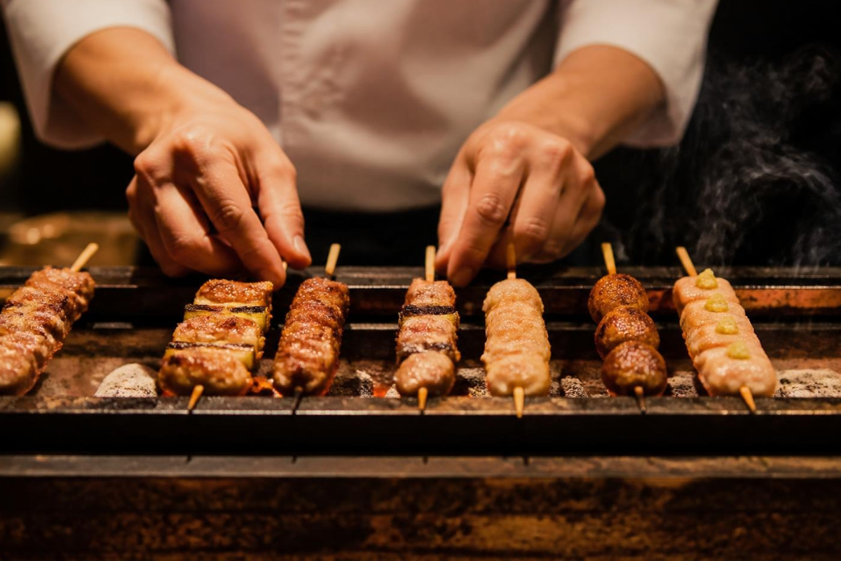 Professional chef grilling food over smokeless binder free sawdust charcoal on a Japanese BBQ grill.