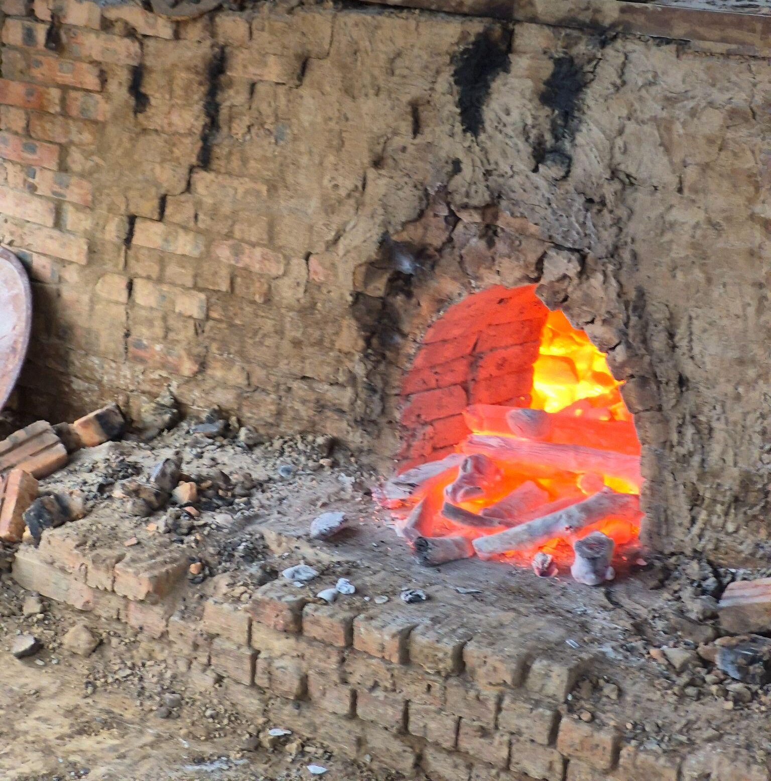 Traditional brick kiln with glowing fire inside, demonstrating the production process of high-quality charcoal